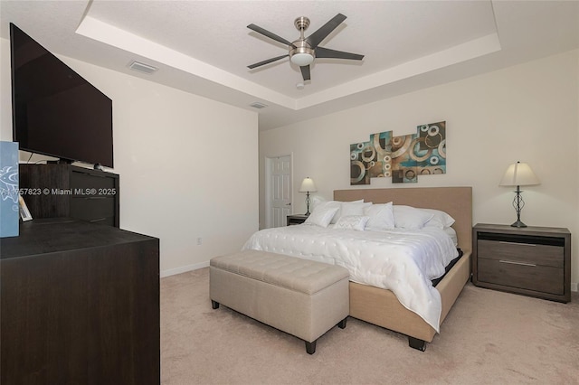 bedroom with visible vents, light carpet, a raised ceiling, a ceiling fan, and baseboards