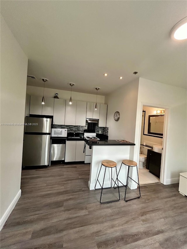 kitchen with dark wood-type flooring, white appliances, dark countertops, and white cabinetry