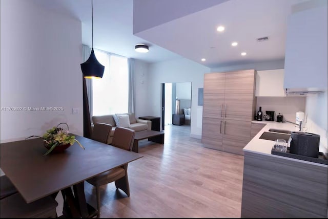 kitchen featuring visible vents, light countertops, light wood-style floors, modern cabinets, and a sink