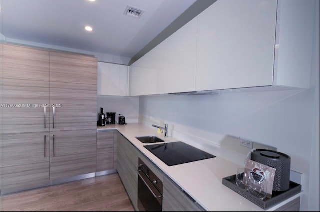 kitchen featuring visible vents, a sink, light countertops, black appliances, and modern cabinets