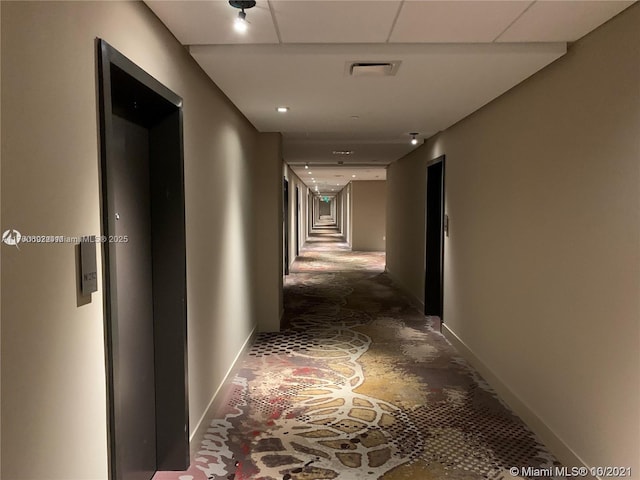 corridor with visible vents, concrete flooring, stairs, and baseboards