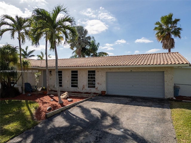 ranch-style house featuring a tile roof, aphalt driveway, a garage, and stucco siding