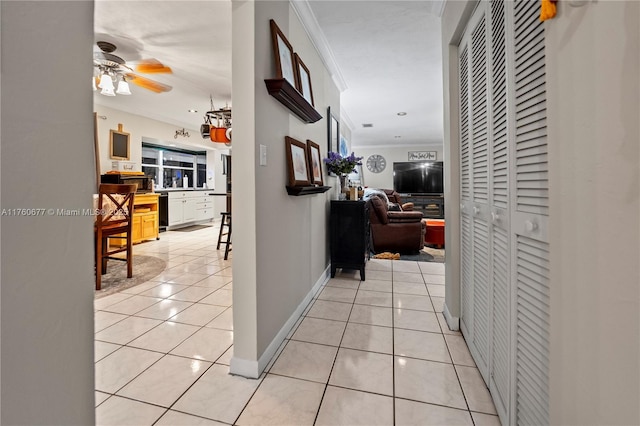 hall with light tile patterned floors, baseboards, and ornamental molding