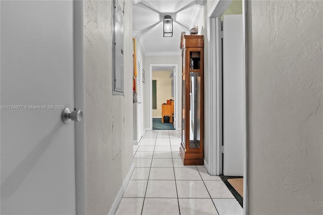 hallway featuring light tile patterned floors, a textured wall, baseboards, and ornamental molding