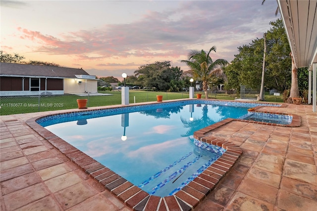 pool at dusk featuring a patio area, a lawn, an outdoor pool, and fence