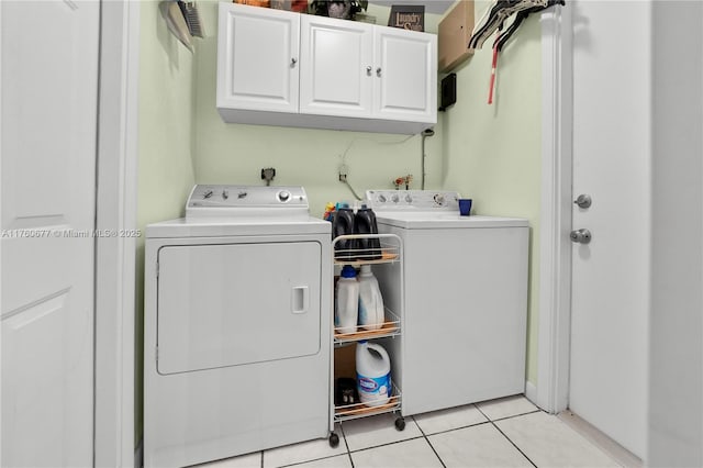 washroom with light tile patterned floors, cabinet space, and washer and dryer