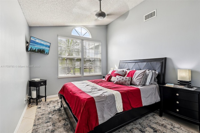 bedroom with visible vents, baseboards, lofted ceiling, tile patterned floors, and a textured ceiling