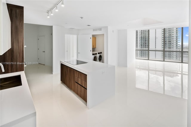 kitchen with a center island, washer and dryer, modern cabinets, black electric cooktop, and a sink