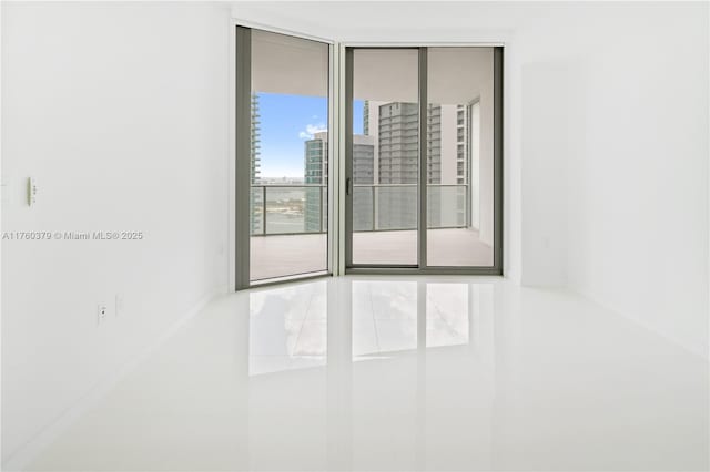 unfurnished room with tile patterned floors, floor to ceiling windows, and baseboards