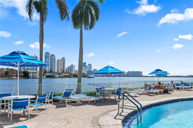 view of pool with a patio, a view of city, and a water view