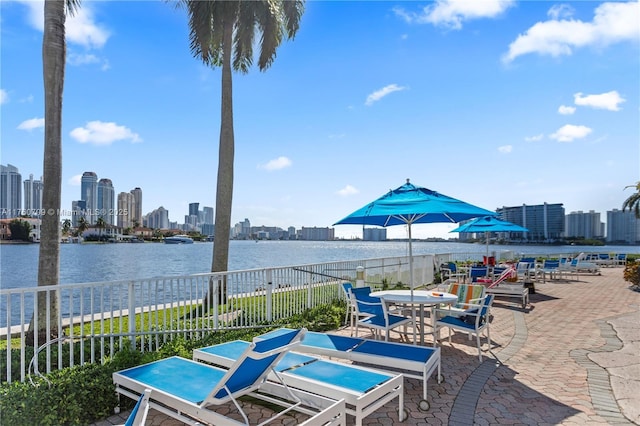 view of patio / terrace with a view of city, fence, and a water view