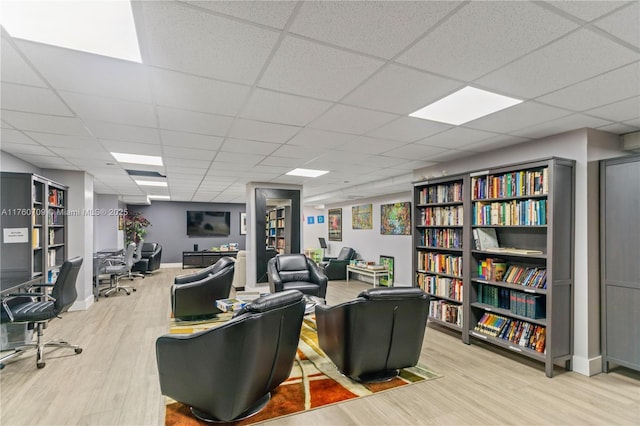 interior space featuring a paneled ceiling, baseboards, and wood finished floors