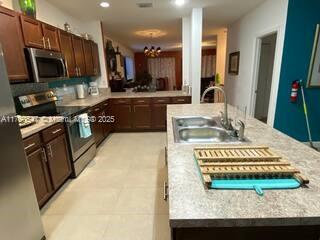 kitchen with recessed lighting, a sink, light countertops, dark brown cabinets, and appliances with stainless steel finishes