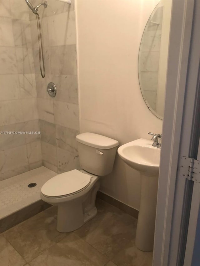 bathroom with toilet, baseboards, a stall shower, and a sink