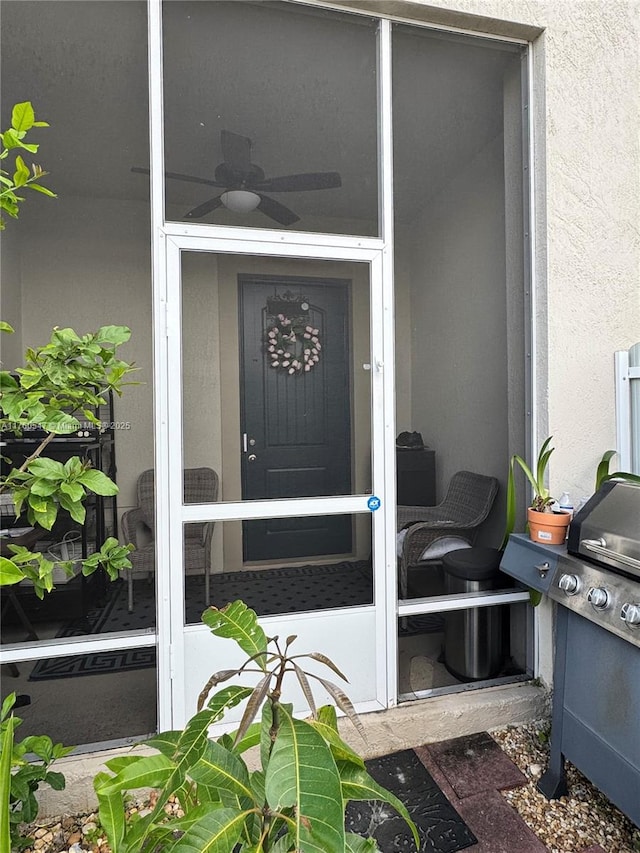 property entrance with a ceiling fan and stucco siding