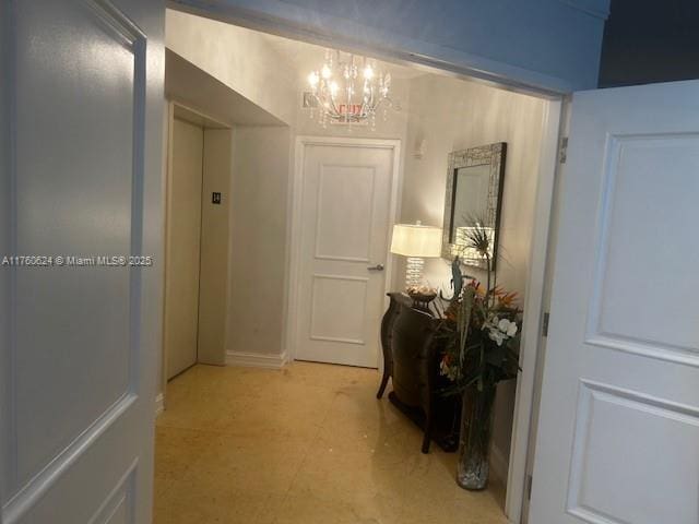 corridor with light floors and a chandelier