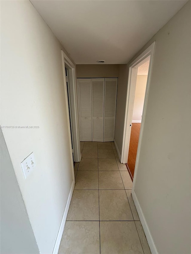 corridor featuring light tile patterned floors and baseboards