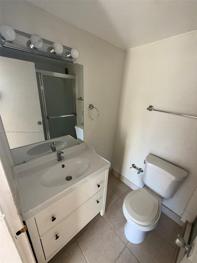 bathroom with tile patterned flooring, baseboards, toilet, a stall shower, and vanity