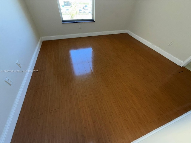 empty room featuring dark wood-style floors and baseboards