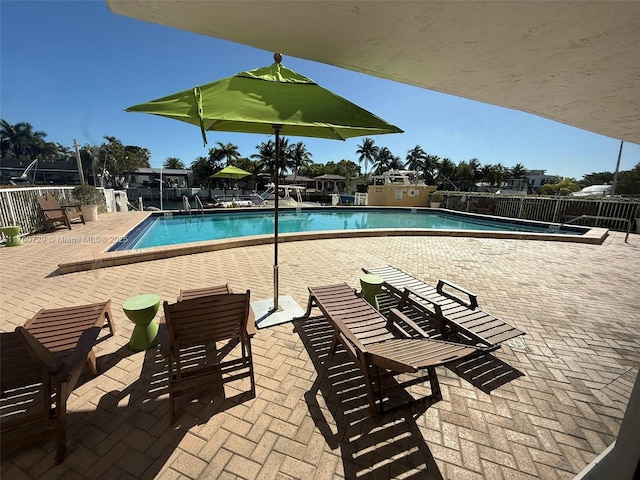 community pool with a patio area and fence