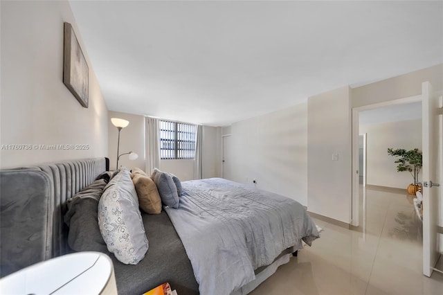 bedroom with light tile patterned floors and baseboards