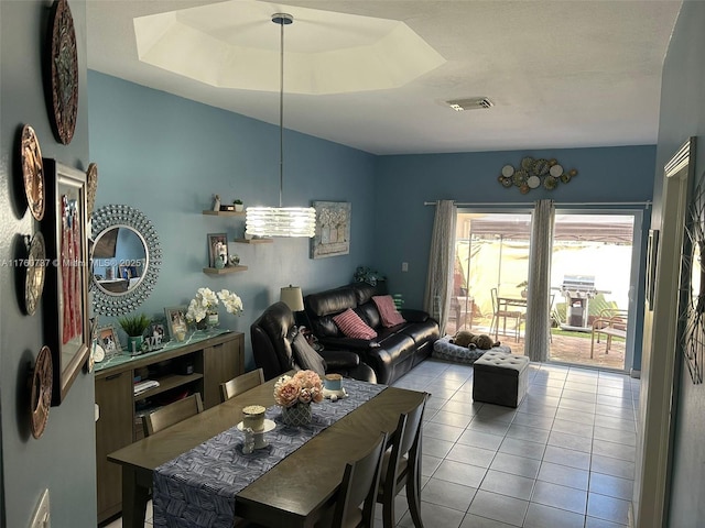 dining space with tile patterned floors, visible vents, and a tray ceiling