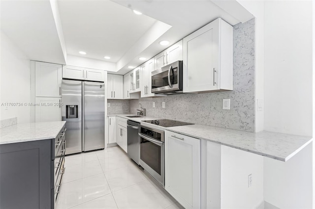 kitchen with light stone counters, tasteful backsplash, appliances with stainless steel finishes, and white cabinets