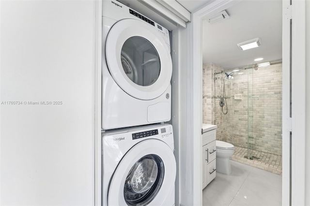 laundry area with light tile patterned floors, stacked washer and clothes dryer, and laundry area