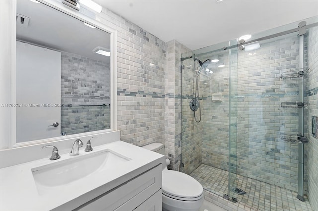 bathroom featuring visible vents, toilet, a stall shower, and vanity