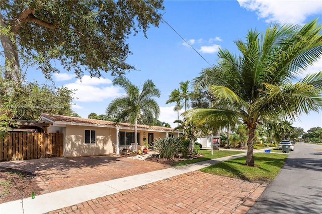 single story home with a tile roof, fence, a front lawn, and stucco siding