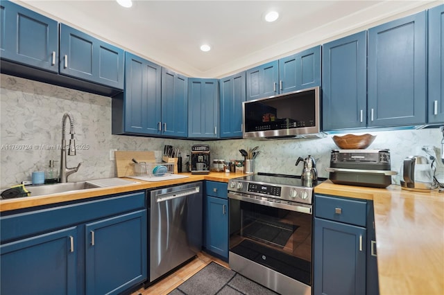 kitchen with blue cabinetry, a sink, tasteful backsplash, appliances with stainless steel finishes, and light tile patterned flooring