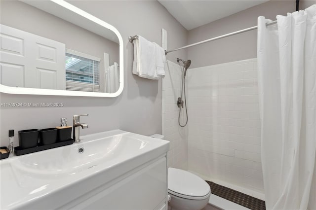 full bath featuring a tile shower, toilet, and vanity