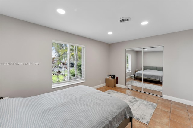 bedroom with light tile patterned floors, visible vents, multiple windows, and baseboards