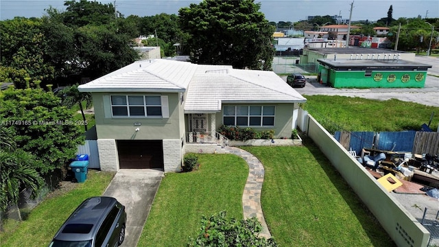 view of front of property featuring fence, concrete driveway, a front yard, stucco siding, and an attached garage