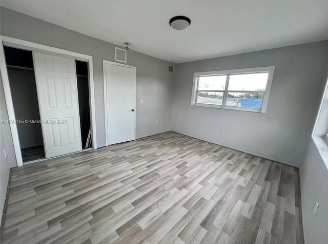 unfurnished bedroom featuring a closet, visible vents, and light wood-type flooring