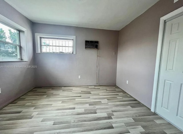 unfurnished room featuring a wall mounted AC and wood finished floors