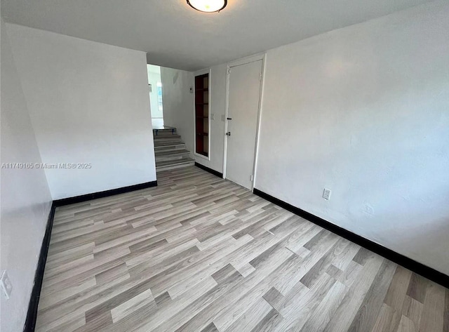 empty room featuring light wood finished floors and baseboards