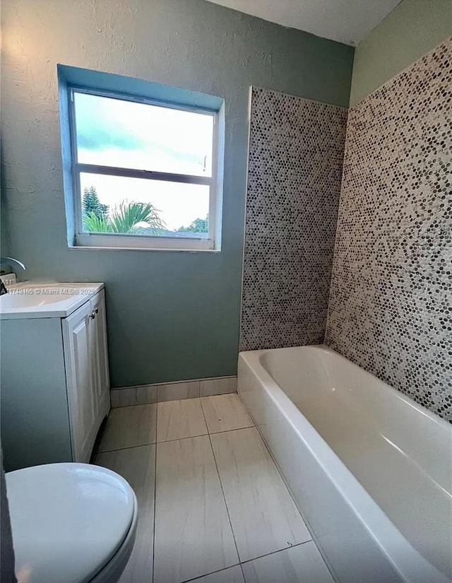 bathroom with vanity, toilet, a textured wall, and baseboards