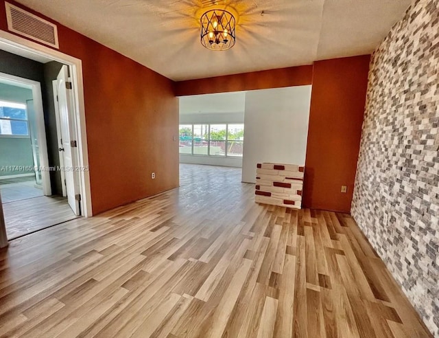 spare room featuring visible vents, a notable chandelier, and wood finished floors