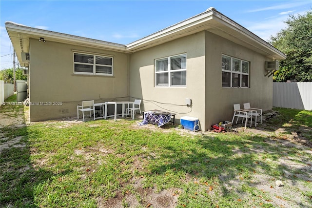 rear view of property featuring stucco siding, a yard, fence, and crawl space