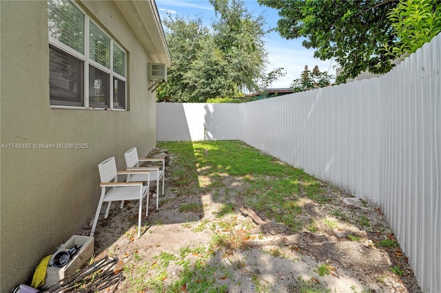 view of yard featuring a wall unit AC and a fenced backyard