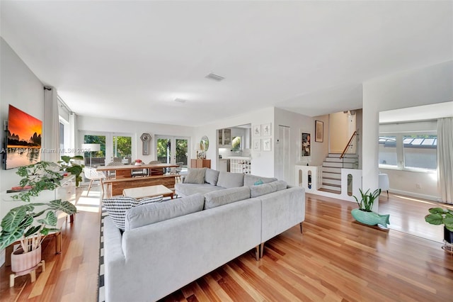 living room featuring stairway, visible vents, and wood finished floors