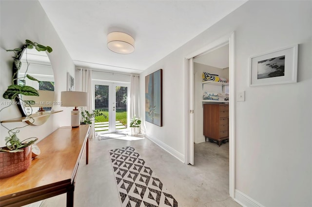 corridor with finished concrete flooring, french doors, and baseboards