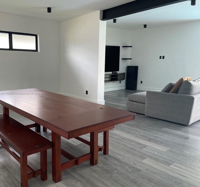 dining area with beam ceiling, light wood-style flooring, and baseboards