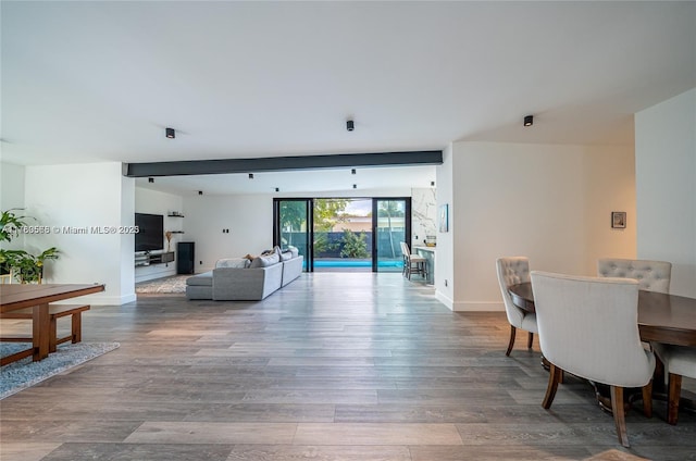 dining space featuring beam ceiling, floor to ceiling windows, baseboards, and wood finished floors