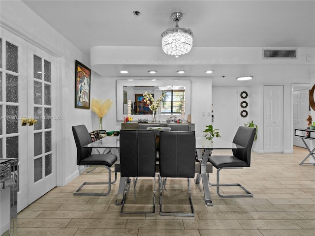 dining space with a notable chandelier, french doors, visible vents, and wood finish floors