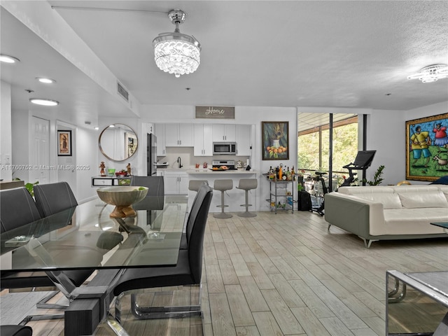 dining area featuring visible vents, light wood-style flooring, and a chandelier