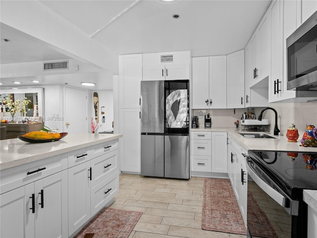 kitchen with a sink, stainless steel appliances, visible vents, and white cabinetry