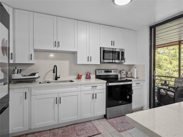 kitchen featuring white cabinetry, light wood finished floors, appliances with stainless steel finishes, and a sink