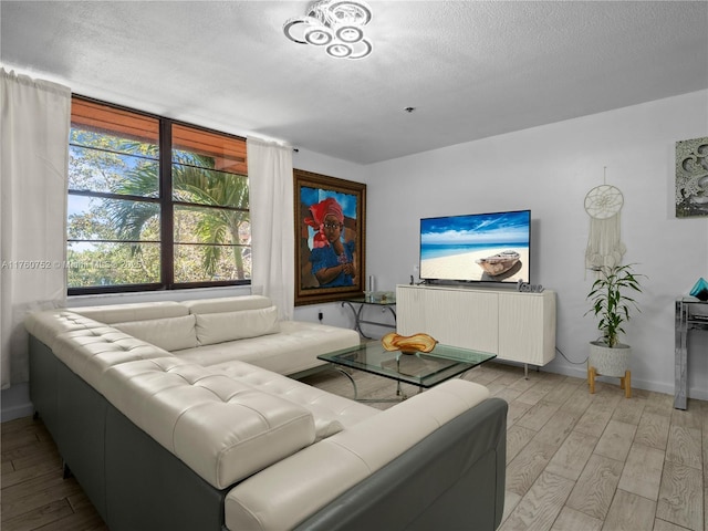 living area featuring baseboards, light wood-type flooring, and a textured ceiling